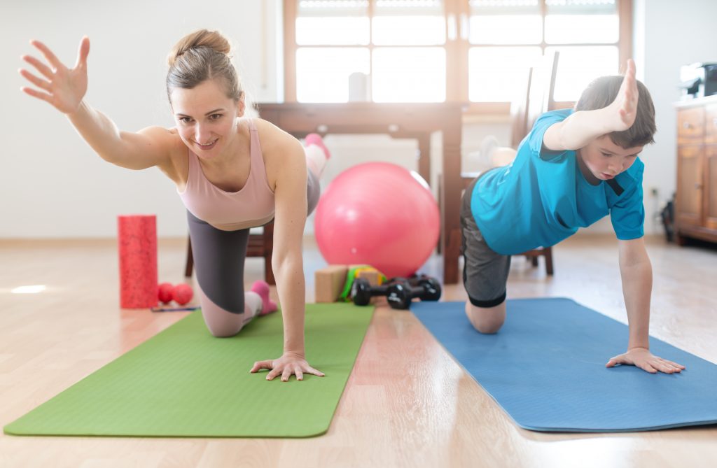 Mam a'i mab ar y llawr yn gwneud yoga yn ystod Covid-19