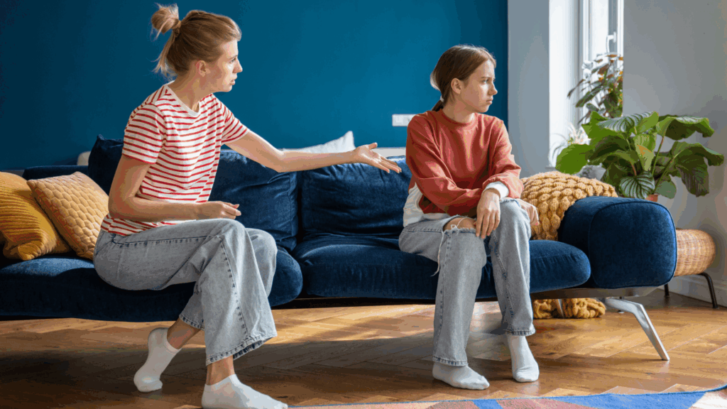 Mum shouting at teenage girl on a sofa whilst she looks away
