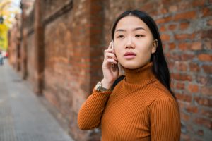 Young Asian woman talking on the phone outdoors in the street - for worried about friend on social media article