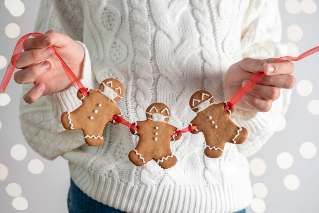 Person holding a row of christmas gingerbread men with a masks for latest Covid-19 rules article