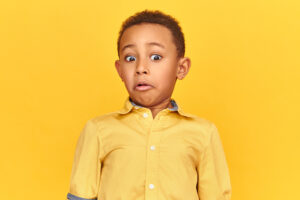 Young boy in yellow shirt recoiling with shock on his face. For online safety article