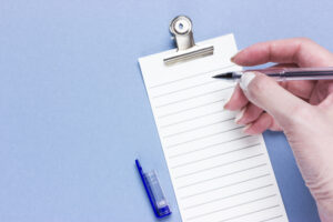 Ruled paper with hand holding pen ready to write