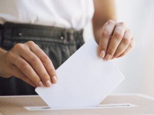 Woman's hands placing vote in ballot box