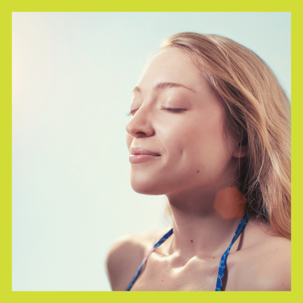 Blonde woman with eyes closed inhaling through nose with smile on face