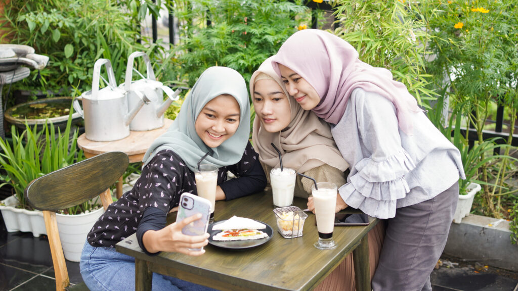 Three girls wearing head veil taking a selfie and smiling