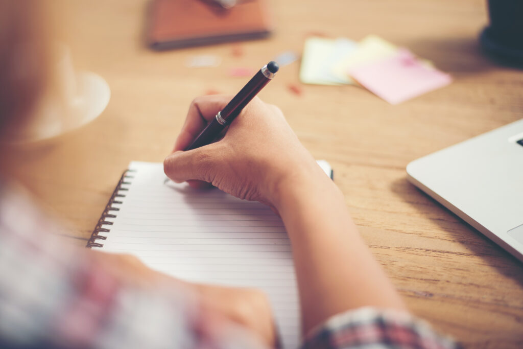 Someone holding pen writing down in book for sad article