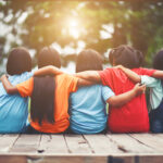 Group of young friends sat down with arms around each other for Survival Guide To Starting Secondary article