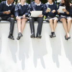 Five people in schools uniform sat on wall for Survival Guide To Starting Secondary article