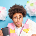 Puzzled girl with glasses with memo stickers behind stuck on cotton wool clouds for University guide blog