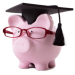 Pink piggy bank dressed as a college graduate with mortar board and glasses.  Isolated on white.