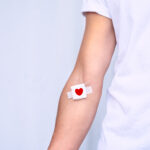 Blood donor with bandage with red heart depicting after giving blood