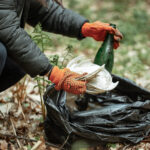 A volunteer with a rubbish bag cleans up litter outside