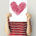 kid holding heart icon on a paper