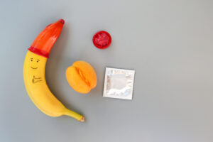 Banana with smiley face and thumbs up with condom as a hat