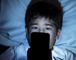 Young boy lying in bed on phone