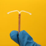 Doctor holding T-shaped intrauterine birth control device - contraception