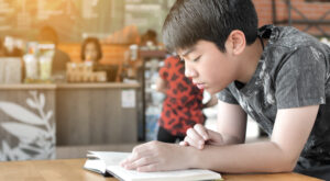 Asian boy reading a book pensively for dyslexia blog