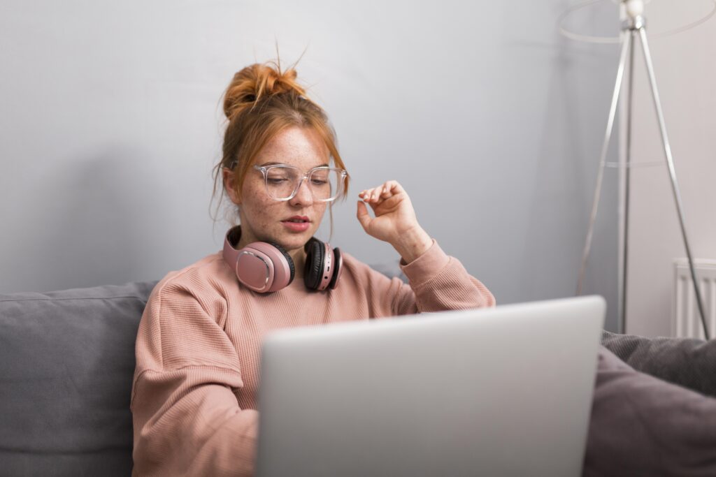 Young girl using laptop on sofa with headphones