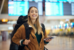 Airport, travel and portrait of woman with passport, flight ticket or information of immigration, journey and backpack. Young person, identity document and international registration. faq or about us.