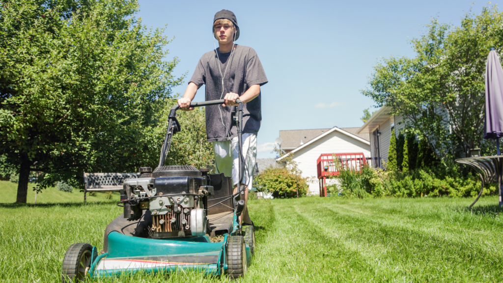 Teenage boy mowing the lawn