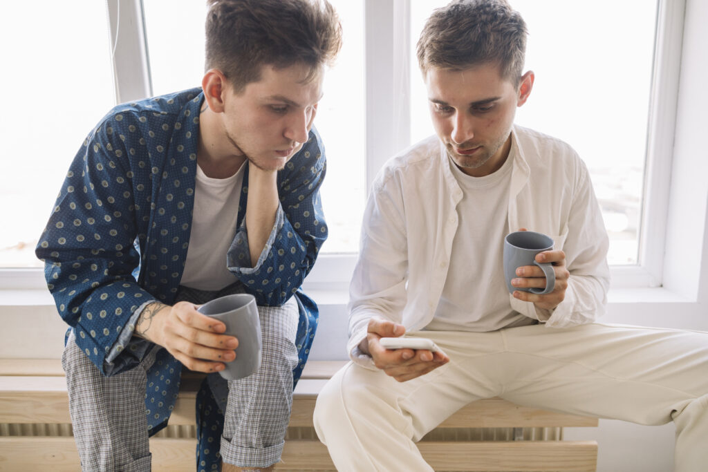 Two boys looking at a phone, both look like they are thinking about something. 