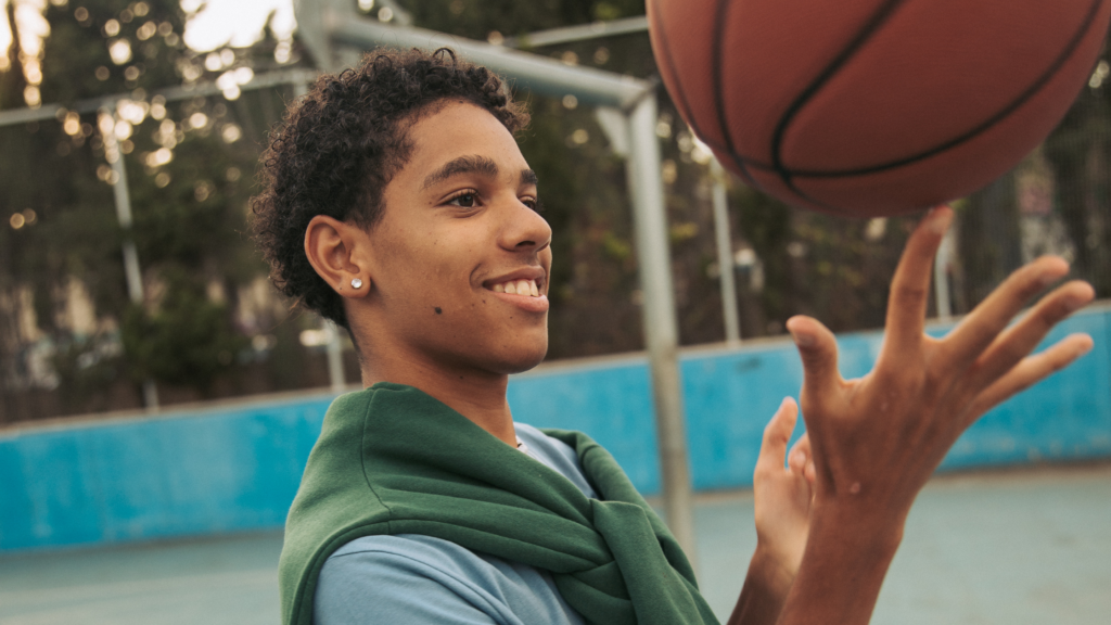 Young boy with his ears pieces balancing a basketball on his finger on a basketball court
