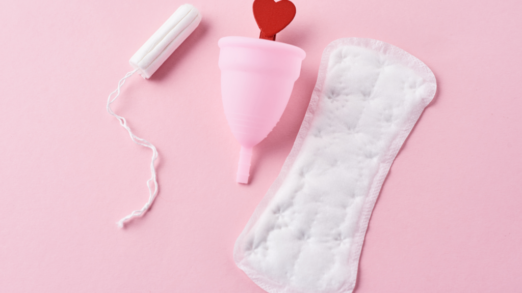 Tampon, menstrual cup and period pad on a pink backround