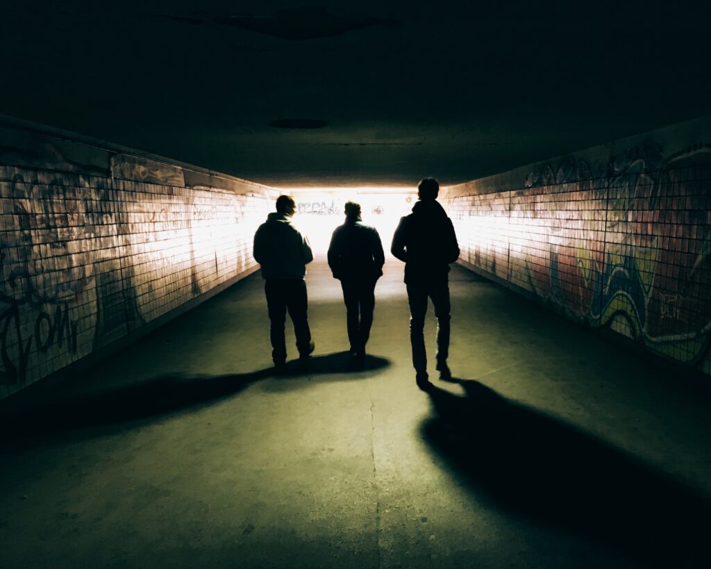 three people walking in a dark tunnel