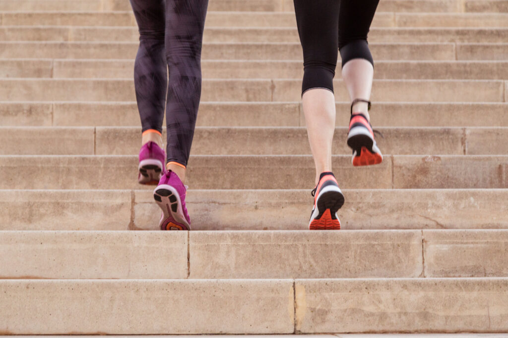 Two women walking up staris wearing trainers