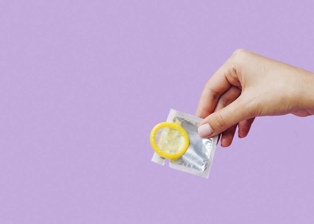 close up of a woman holding a condom
