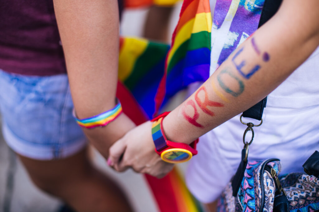 Dau berson yn dal dwylo yn Pride