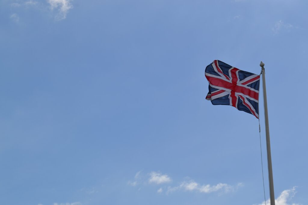 a picture of a Union Jack flag on a pole against a blue sky
