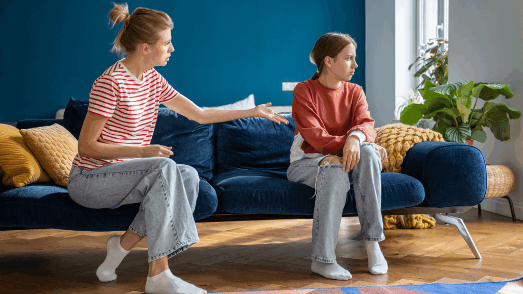 Mum shouting at teenage girl on a sofa whilst she looks away